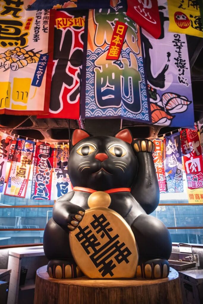 Maneki-neko negro con moneda dorada en NÖMI